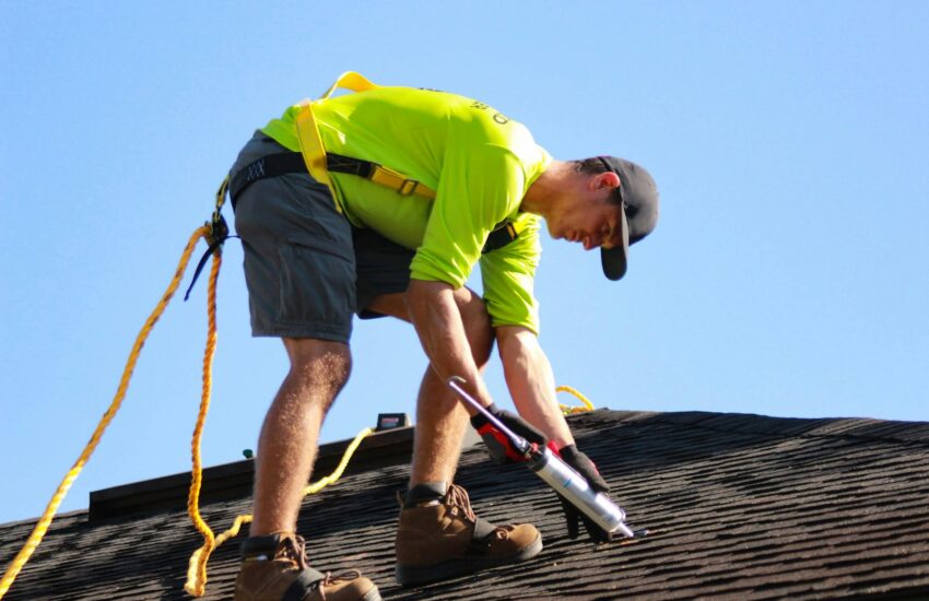 a man in a yellow shirt is working on a roof